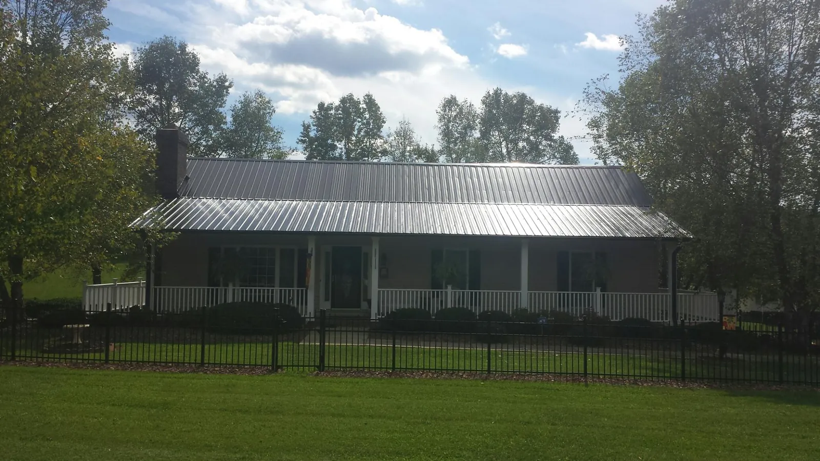 Gray metal roof on a brick ranch with a full width front porch — Gutter Guard Installation work by our crew in Bloomfield